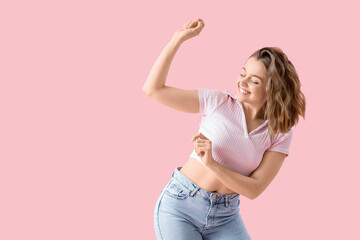 Cool young woman dancing on pink background