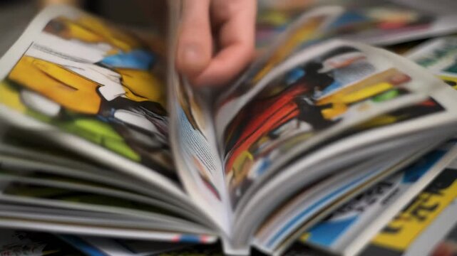 Close-up of a hand flipping through the vibrant, illustrated pages of a comic book, surrounded by other comics.