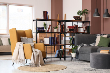Comfortable armchair, sofa and book shelf in interior of living room, closeup