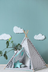 Interior of modern children's room with teepee and houseplant near mint wall, closeup © Pixel-Shot