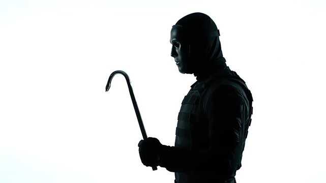 Silhouette of Masked Figure Holding Crowbar Against Bright White Background