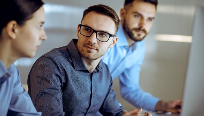 Workplace Collaboration: Focused colleagues deeply engaged in a dynamic discussion around a computer, illustrating professional synergy in action.