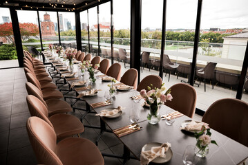 Elegant rooftop event table setup with modern dining décor, floral centerpieces, and panoramic Vilnius city views, arranged for a stylish celebration, wedding reception, or upscale gathering.