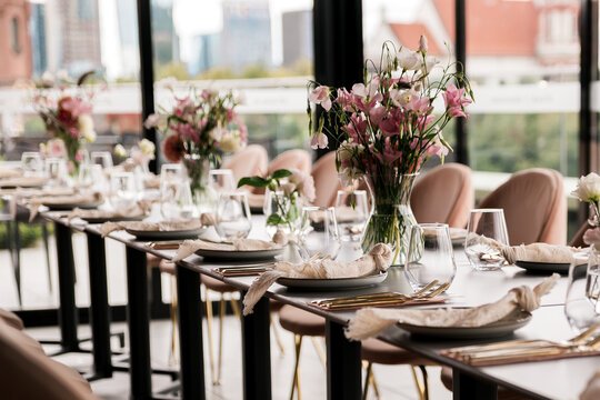 Beautifully arranged event table with elegant floral centerpieces, gold cutlery, and soft neutral linens, creating a refined and sophisticated setting for a celebration or upscale gathering.