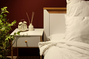 Alarm clock with reed diffuser on nightstand in dark bedroom