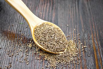 Cumin seeds in spoon on wooden board
