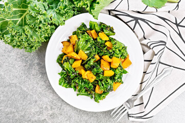 Kale with pumpkin in plate on granite countertop top