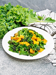 Kale with pumpkin in plate on stone table