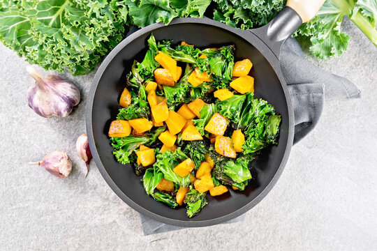 Kale with pumpkin in skillet on stone countertop top