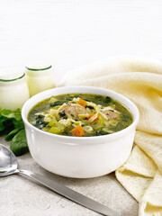 Soup with meatballs and pasta in bowl on granite table