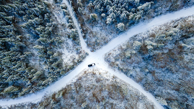 Vue &agrave; vol d'oiseau d'une camionnette stationn&eacute;e &agrave; l'intersection de deux routes enneig&eacute;es en pleine for&ecirc;t