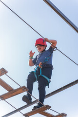 Child boy in Protective Gear Navigating a High Ropes Course in adventure park 
