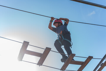 Child boy in Protective Gear Navigating a High Ropes Course in adventure park 