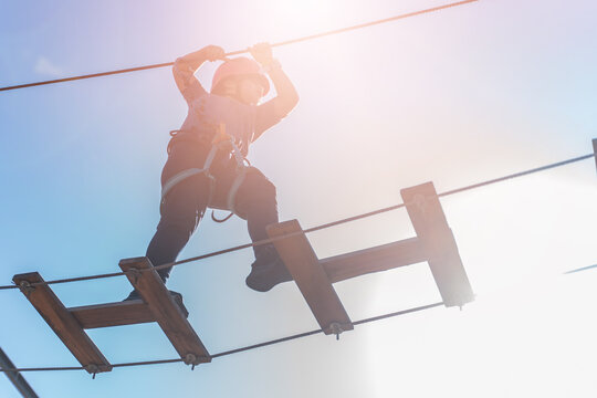 Child boy in Protective Gear Navigating a High Ropes Course in adventure park 