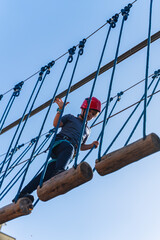 Child boy in Protective Gear Navigating a High Ropes Course in adventure park 