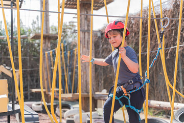 Child boy in Protective Gear Navigating a High Ropes Course in adventure park 