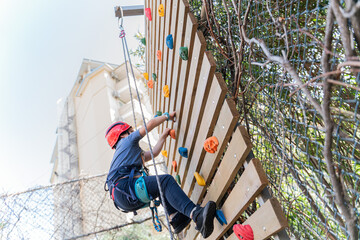 Child boy Rock Climbing on Outdoor Wooden Wall