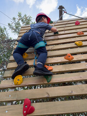 Child boy Rock Climbing on Outdoor Wooden Wall
