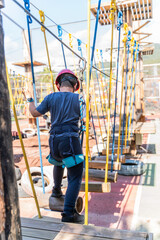 Child boy in Protective Gear Navigating a High Ropes Course in adventure park 