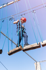 Child boy in Protective Gear Navigating a High Ropes Course in adventure park 
