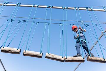 Child boy in Protective Gear Navigating a High Ropes Course in adventure park 