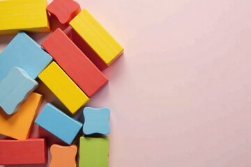 A vibrant collection of colorful wooden blocks arranged on a soft pink background, leaving ample space for text or design elements.