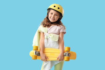 Cute little girl with skateboard and helmet on blue background © Pixel-Shot