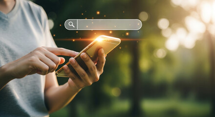A person holds a smartphone with a search bar overlay, set against a blurred green background, bathed in soft sunlight creating a serene, modern scene.