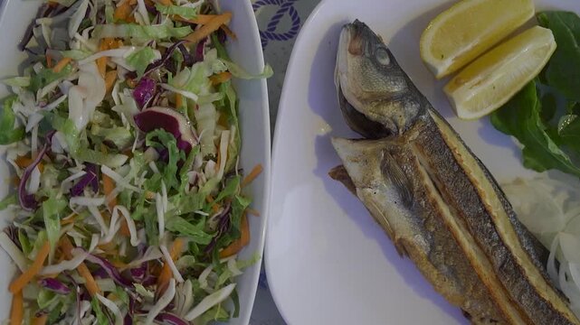 Fresh Salad and Grilled Sea Bass on Restaurant Table
