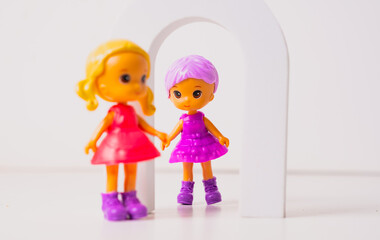 Colorful toy dolls playing together in a vibrant setting with feathers and an arch