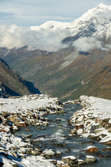 Rocky Creek Covered In Fresh Snow Rushes Over Cliff In The Alps