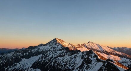 Snow-capped mountains at sunset with a clear blue sky.