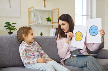 Mother showing cards with sad and happy emoji to smiling daughter to practice communication skills...