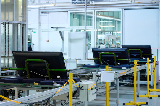 Television assembly line with multiple screens on conveyor in manufacturing plant during daytime operations