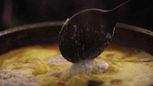 Cooking coconut fish curry. Adding coconut chutney while cooking fish curry.