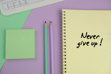 Never give up written on notepad on clean desk