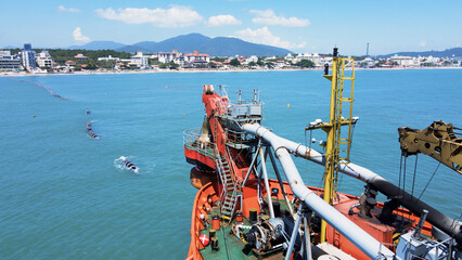 Aerial view of a suction dredger vessel navigating at sea, showing the bow of the vessel, equipment, and machinery used in large-scale dredging operations.