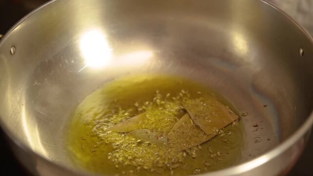 Cooking with bay leaf. Adding bay leaf in hot oil.