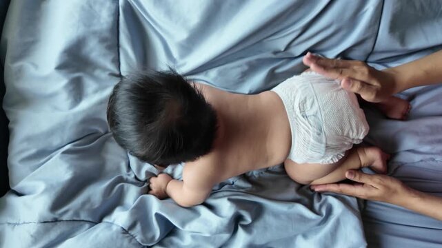 A mother gently patting her baby's bottom to help the infant relax and fall asleep in a cozy bedroom