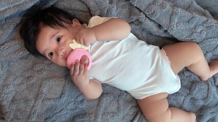 A baby holding a teething toy, exploring it with tiny hands to soothe gums and support early development in a safe, cozy setting