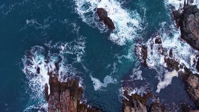 Turquoise waters mingle with rocky shores, creating a stunning contrast as waves crash energetically against the cliffs. The sea reflects the vibrant sky above.