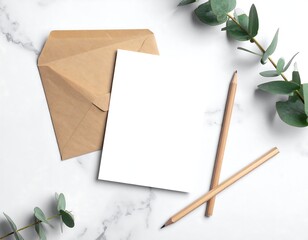 White paper and envelope with pencils and greenery on marble