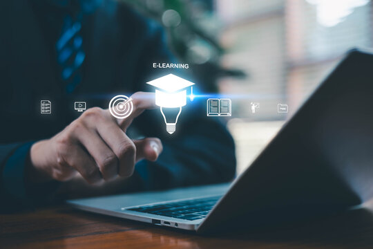 Hand interacting with glowing e-learning icons on a laptop including graduation cap target, book, video lesson, and training symbols, representing digital education, online learning, and modern study. - Powered by Adobe