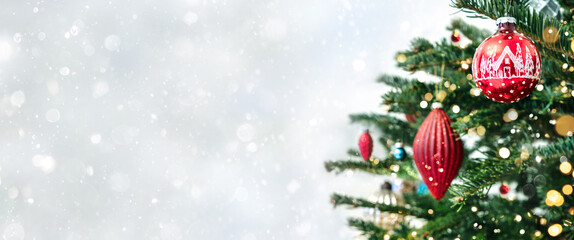 Christmas tree with red decorations on light background with bokeh, sparking, glowing. Merry Christmas and Happy New Year greeting card. Xmas and Winter holidays. Christmas wide banner