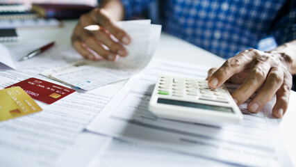 close up shot, asian man calculate expenses from credit card debt and many bills checking bank statement before paying debt