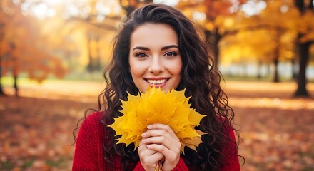 Woman smiling holding yellow leaves in an autumn setting