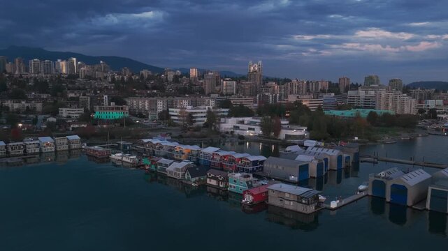 Aerial wide descending shot of floating homes and houseboats on the North Vancouver shore at twilight in British Columbia, Canada. 4K