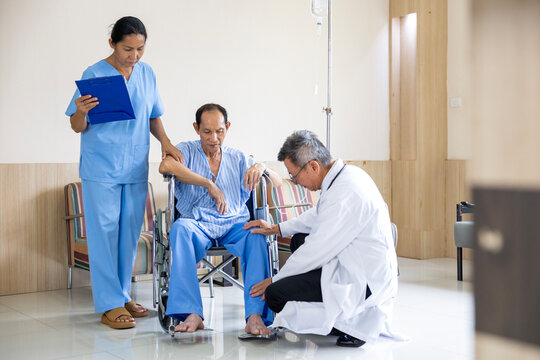 Doctor and nurse are examining patient knee in the wheelchair after operation surgery for rehabilitation and physical therapy and recovery process