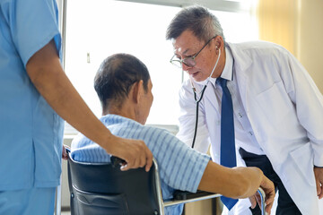 Doctor and nurse are examining patient knee in the wheelchair after operation surgery for rehabilitation and physical therapy and recovery process