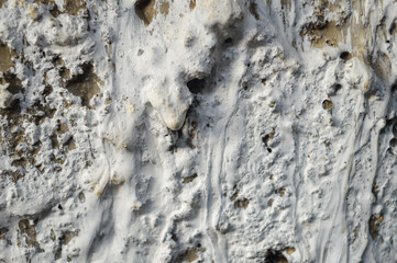 Close-up, abstract texture of a weathered, rough white and gray surface, resembling dried salt deposits, cracked earth, or porous plaster. Concepts of aging, grunge, desert, decay.